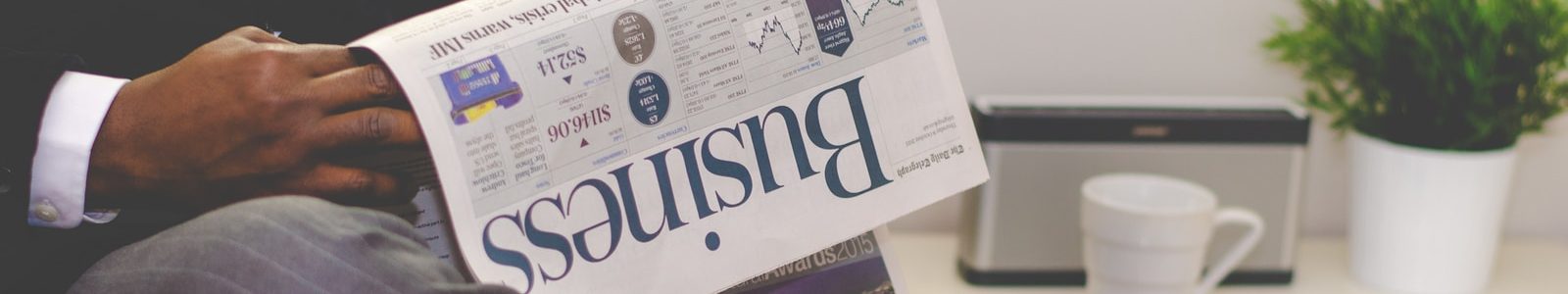 person sitting near table holding newspaper